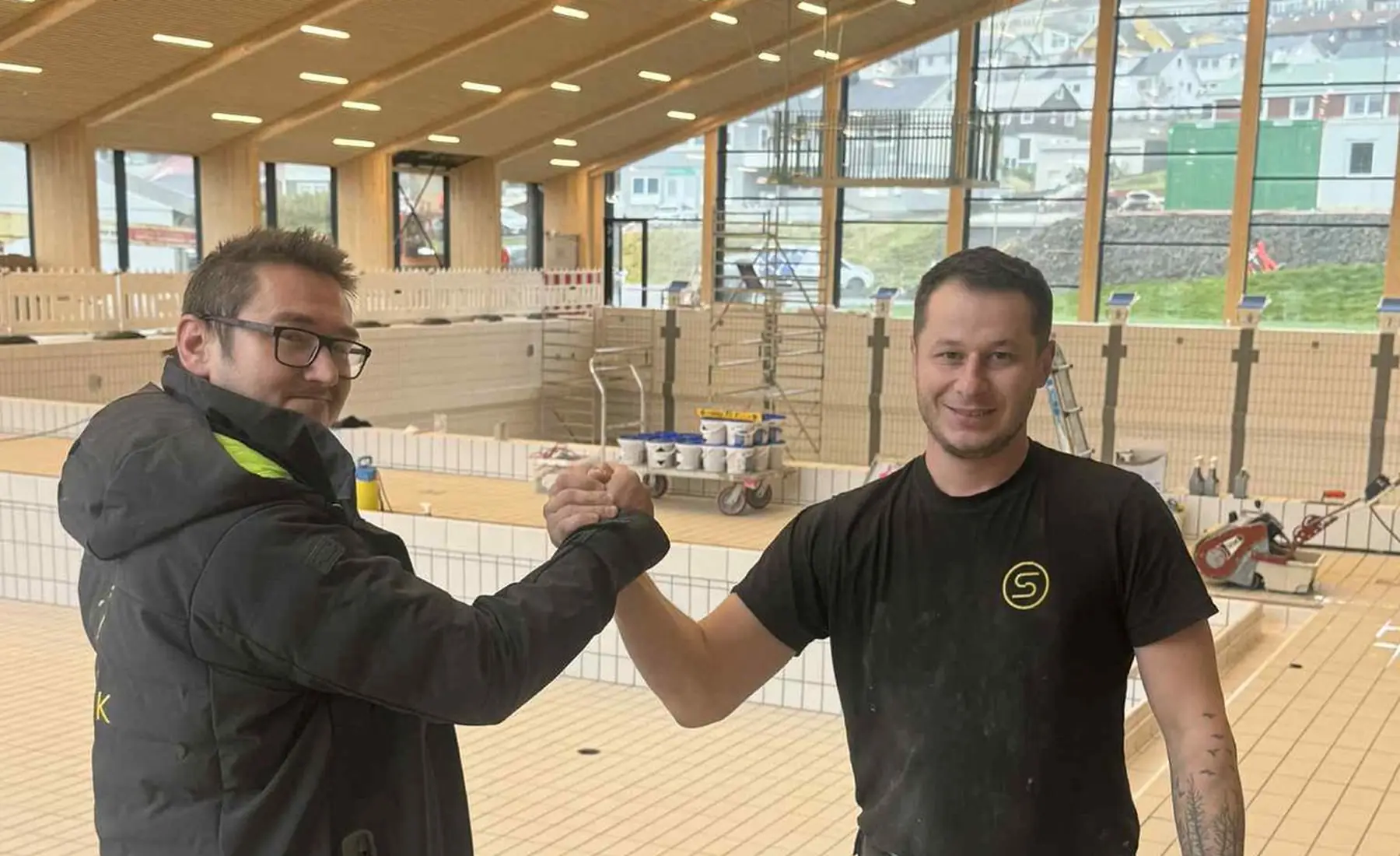 Two STERK crew members inside the finished Bylgjan swimming hall, Runavík